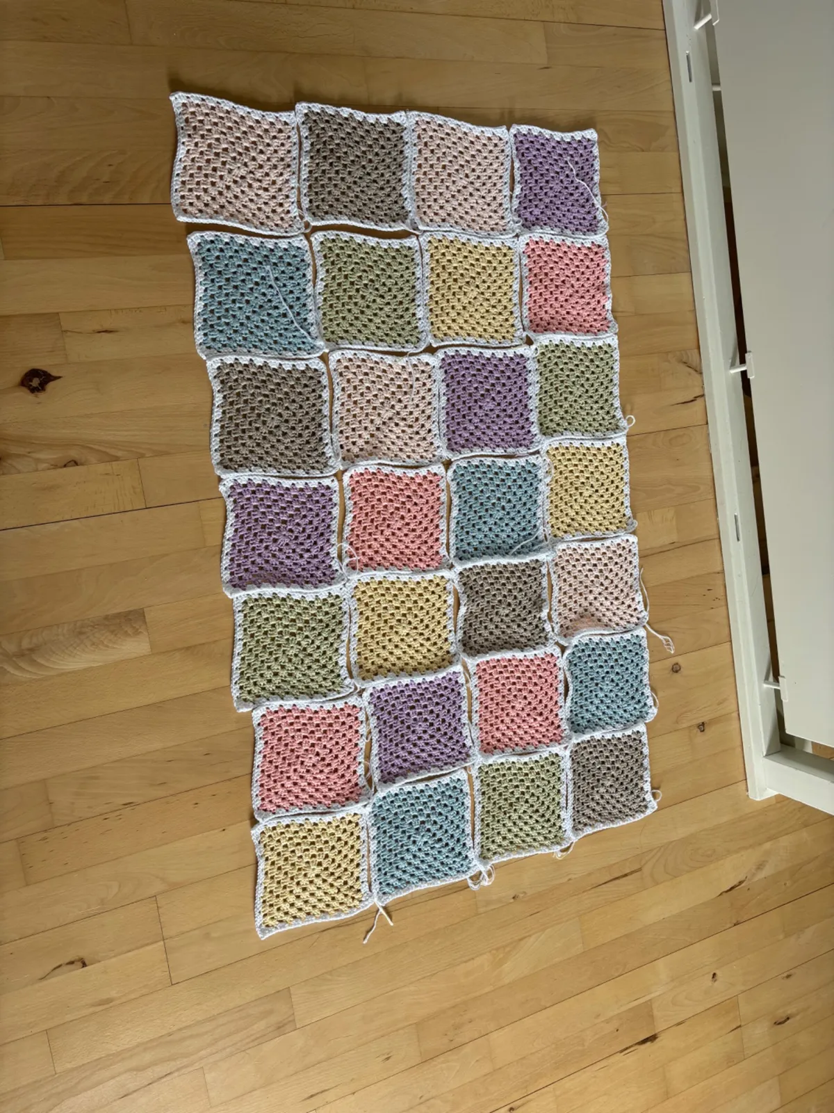 Arctic Squares Blanket undervejs med hæklede pastelfirkanter lagt ud på gulvet